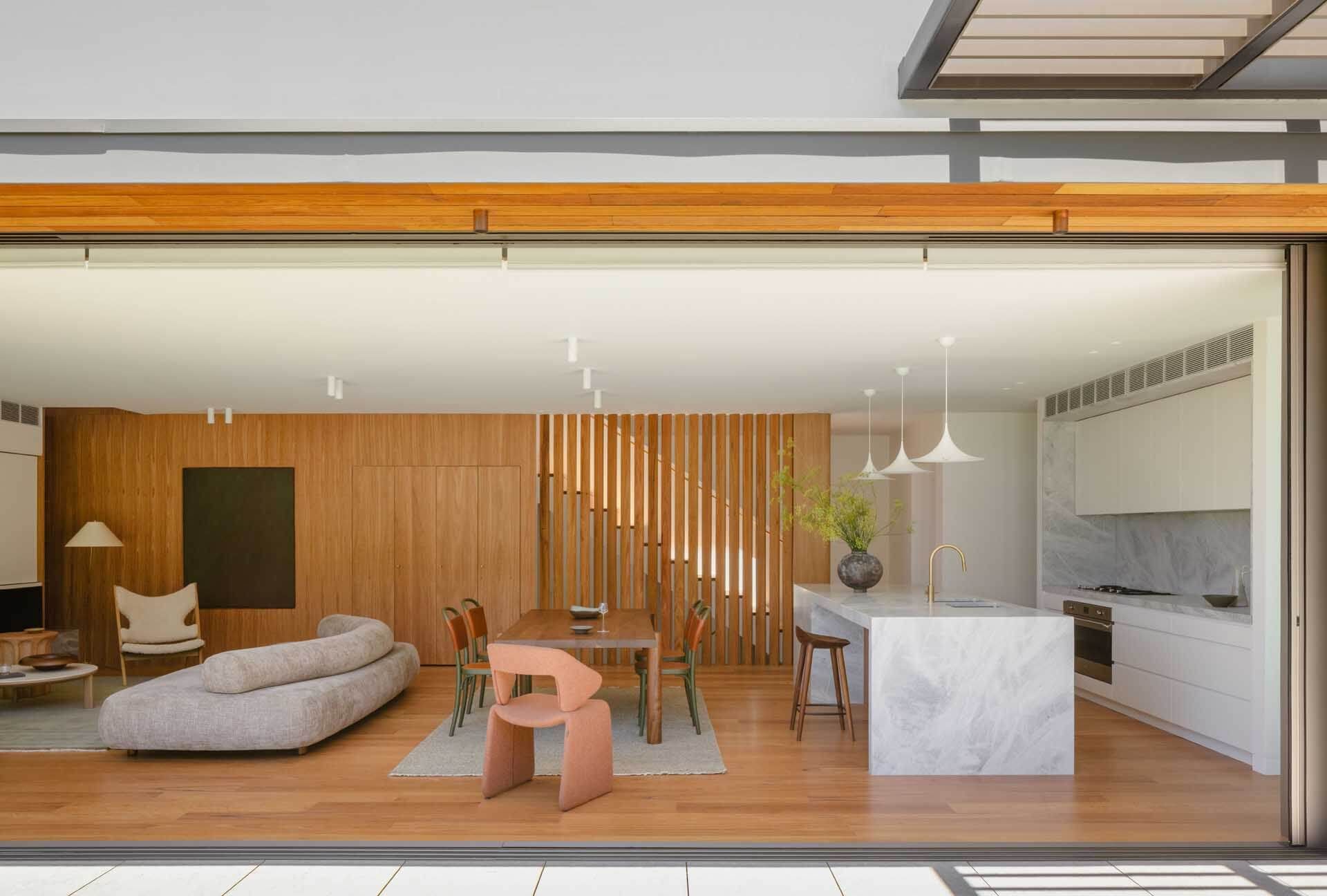 Open plan living room with a timber wall, marble island and a pale sofa