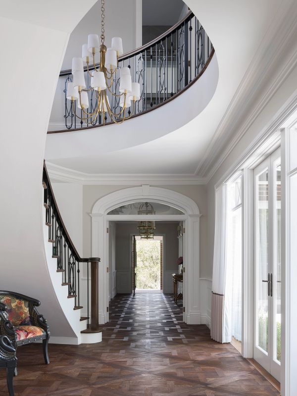 Curved staircase and chandelier in the entry hall at Sussex House