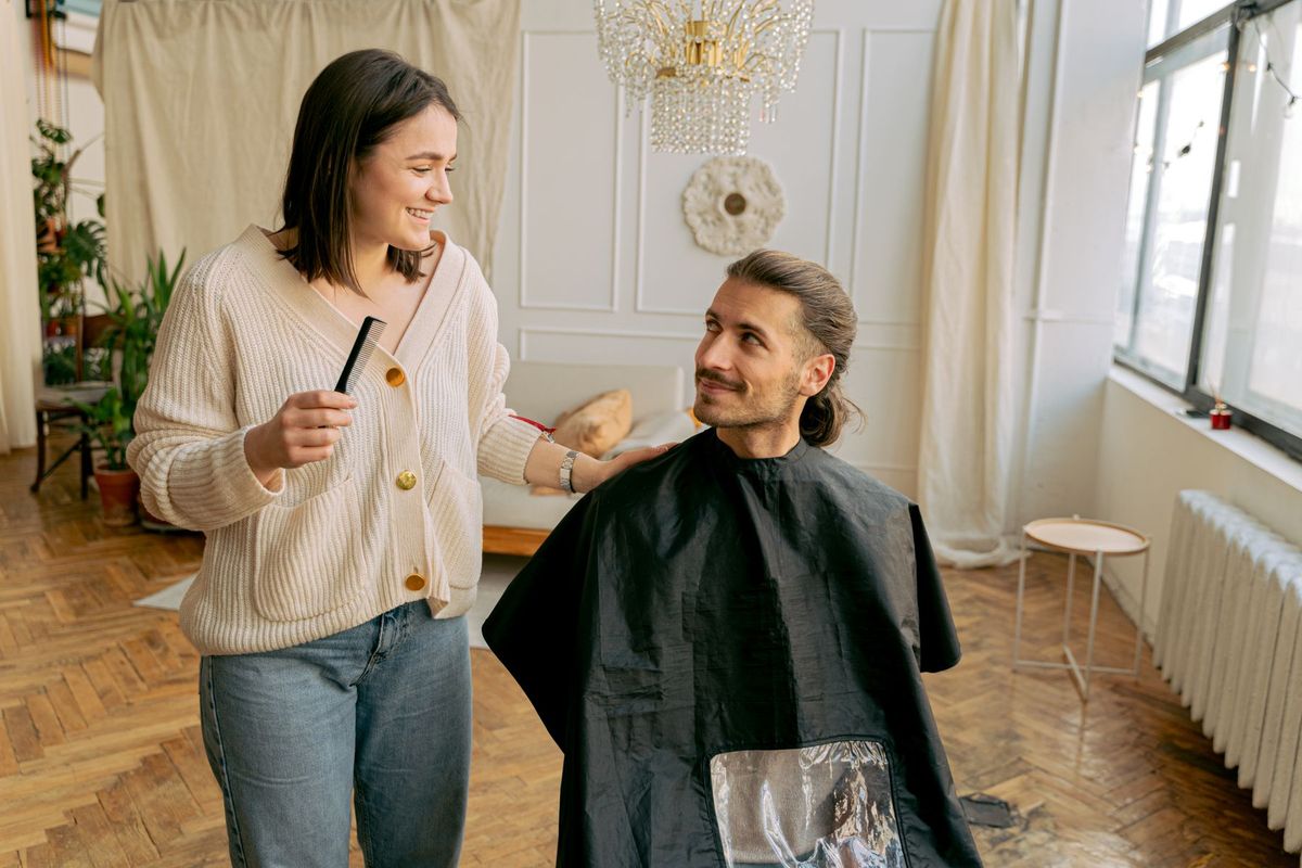 Coiffeuse coiffant un client homme dans un salon professionnel avec ambiance chaleureuse