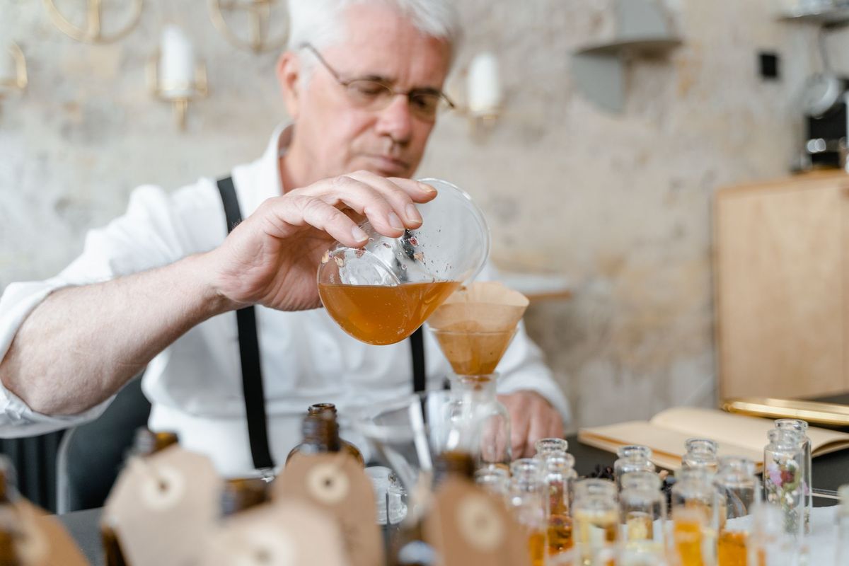 Artisan parfumeur versant précautionneusement des essences dans un flacon en atelier