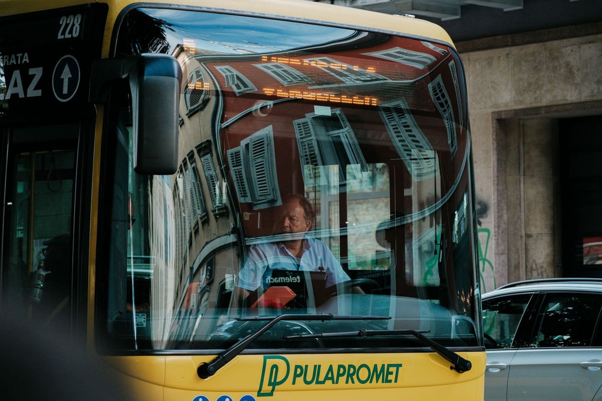 Chauffeur concentré au volant d'un bus, mains sur le volant en circulation urbaine