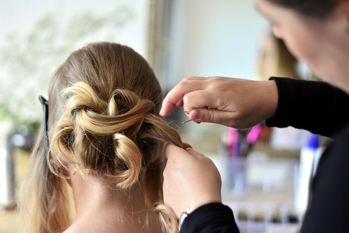 Coiffeur peignant les cheveux d'une cliente dans un salon de coiffure professionnel