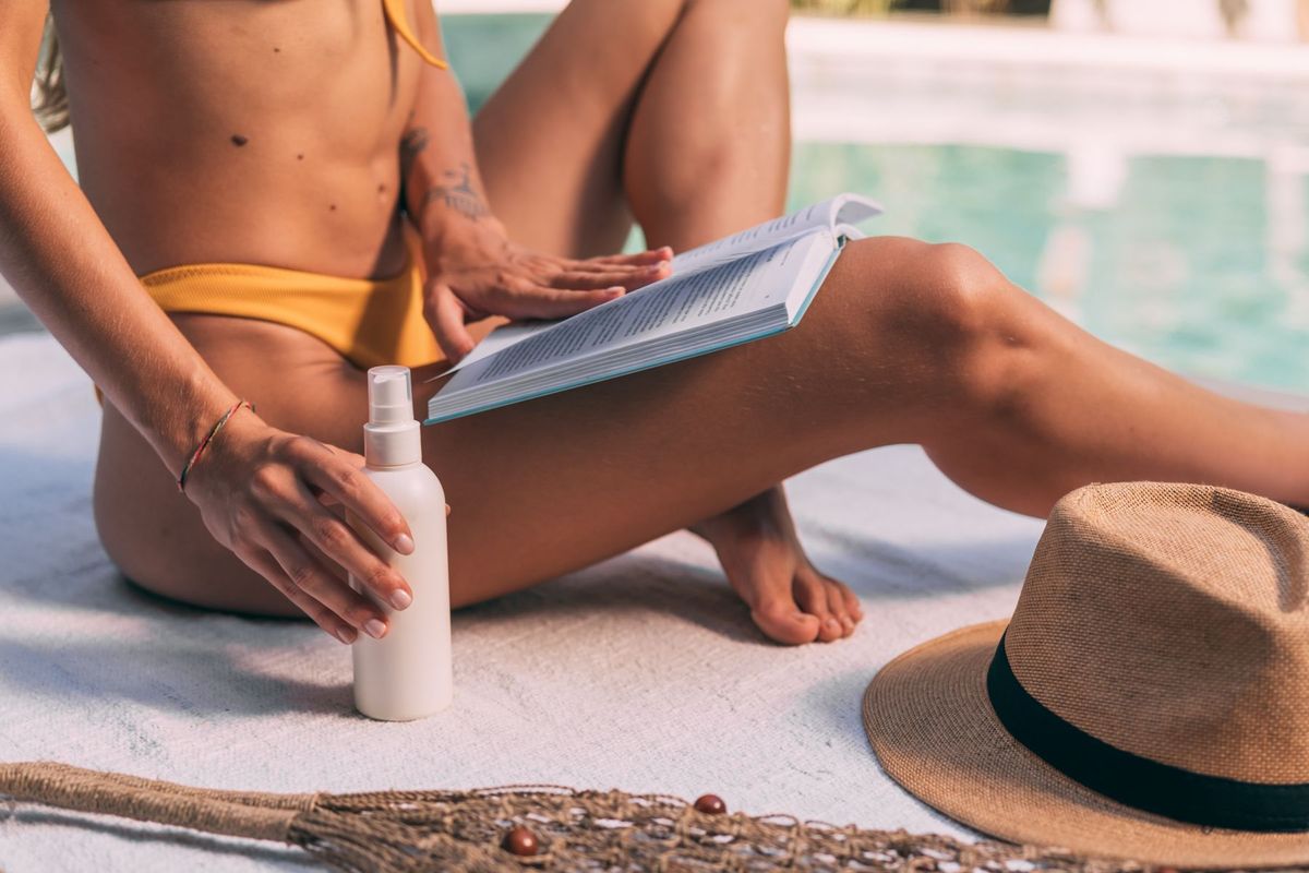 Femme appliquant de la crème solaire sur son bras avant une séance de bronzage