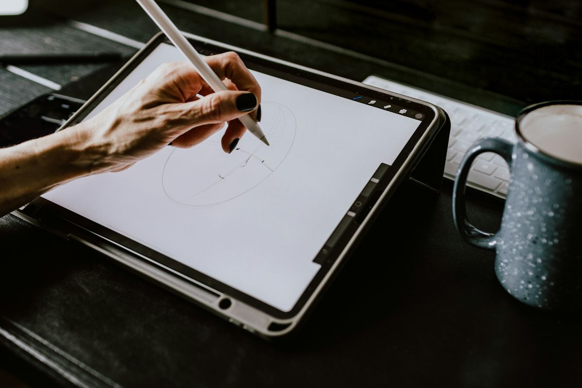 Personne tenant une tablette blanche avec étui noir pour consulter ses créations