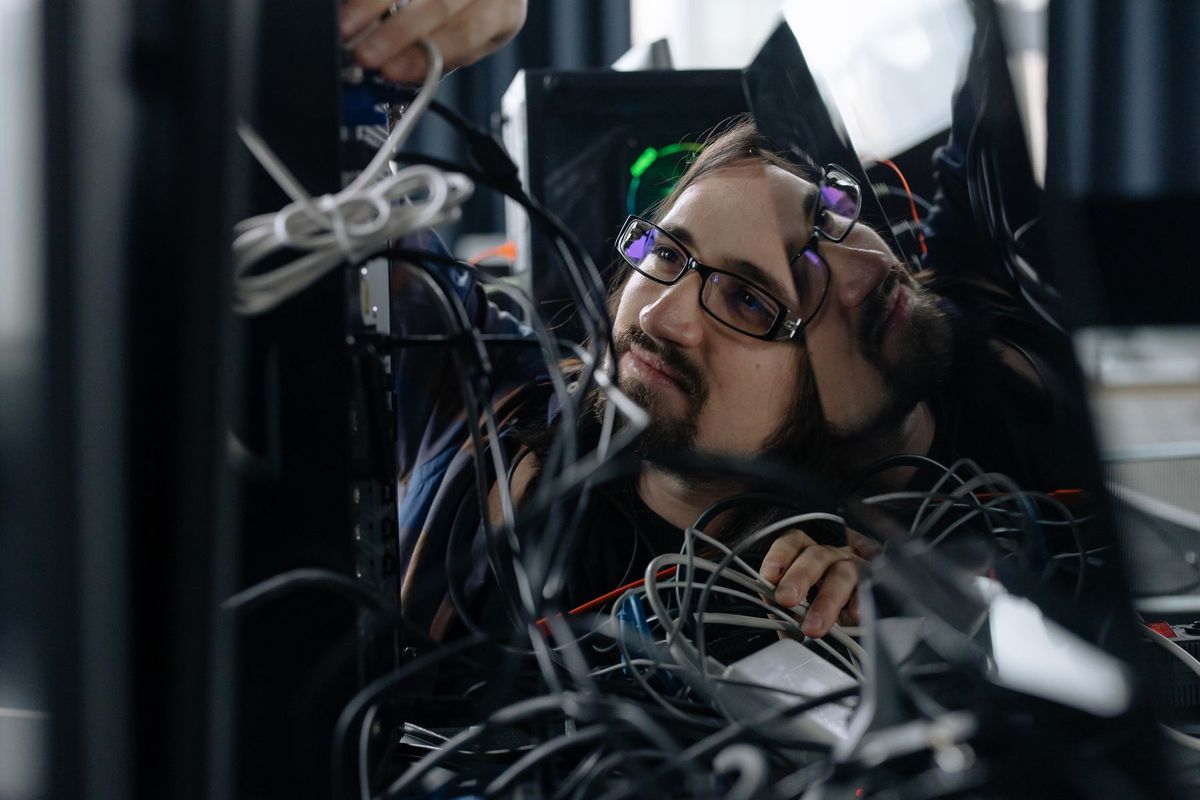 Technicien organisant des câbles informatiques à son poste de travail en environnement professionnel