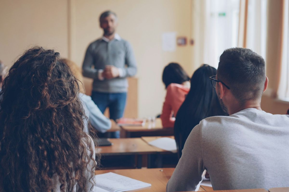 Enseignant expliquant une leçon à des élèves assis à leurs bureaux en classe