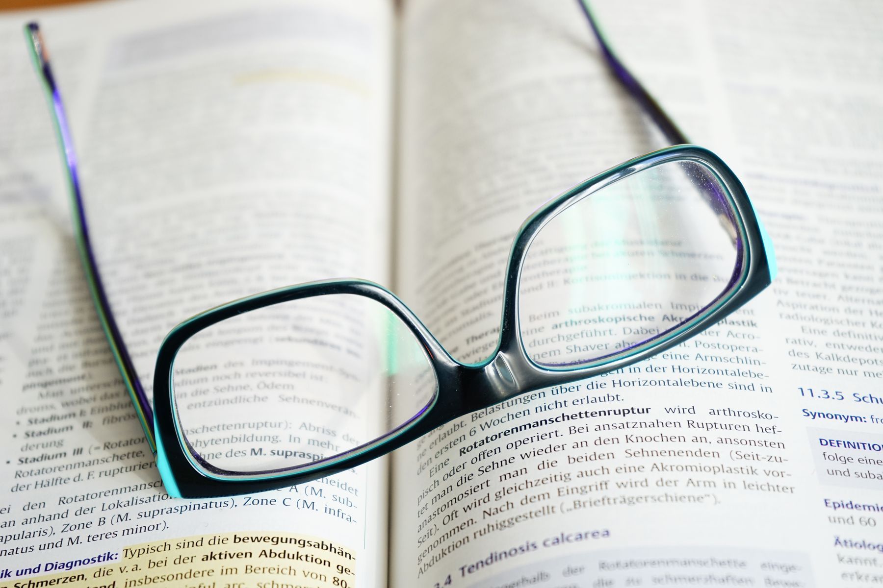 Lunettes de lecture posées sur un manuel ouvert symbolisant l'étude et la transmission de connaissances