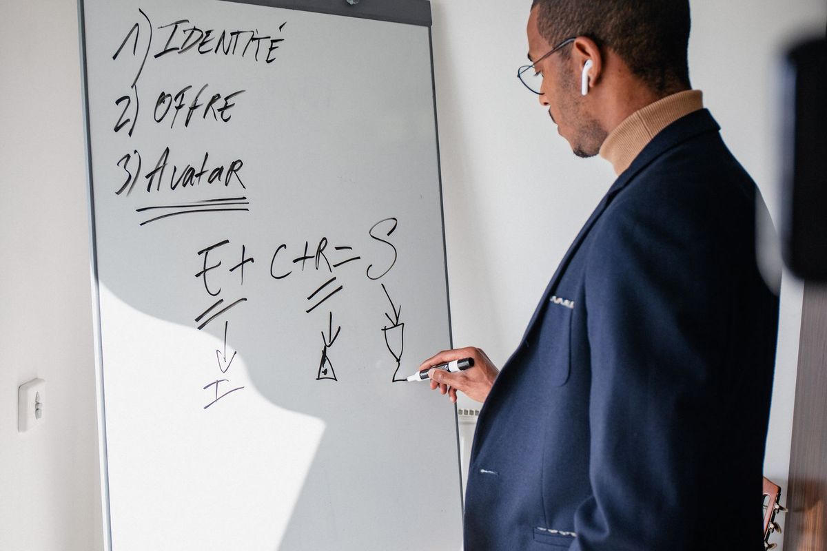 Formateur présentant des concepts stratégiques sur un tableau blanc devant son auditoire