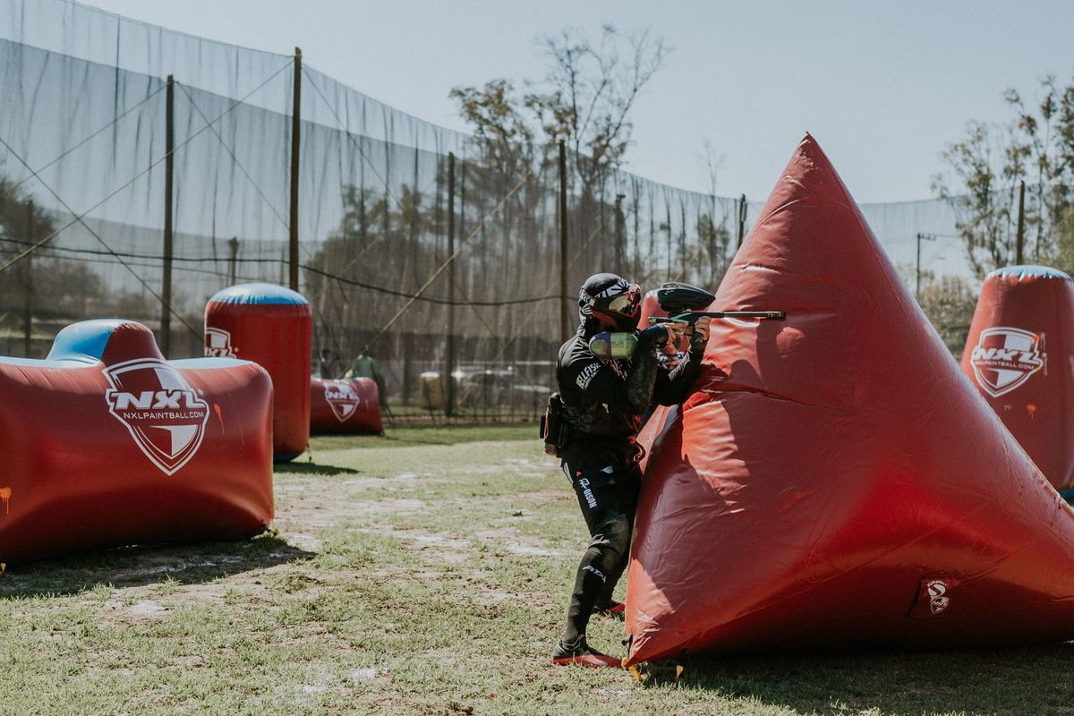 Joueur de paintball accroupi derrière un obstacle gonflable pour élaborer sa stratégie
