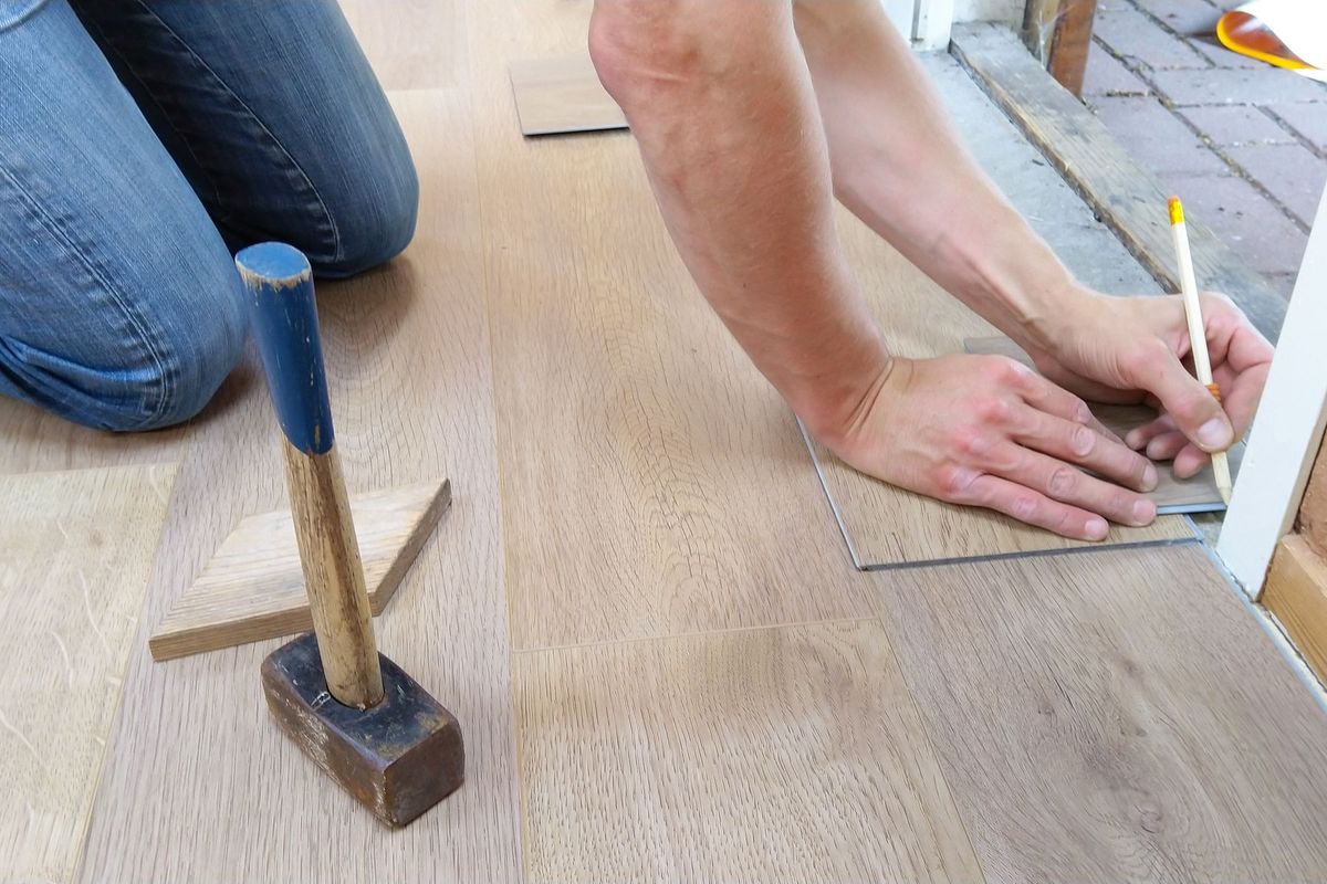 Artisan mesurant et marquant des panneaux de bois pour la pose précise d'un parquet