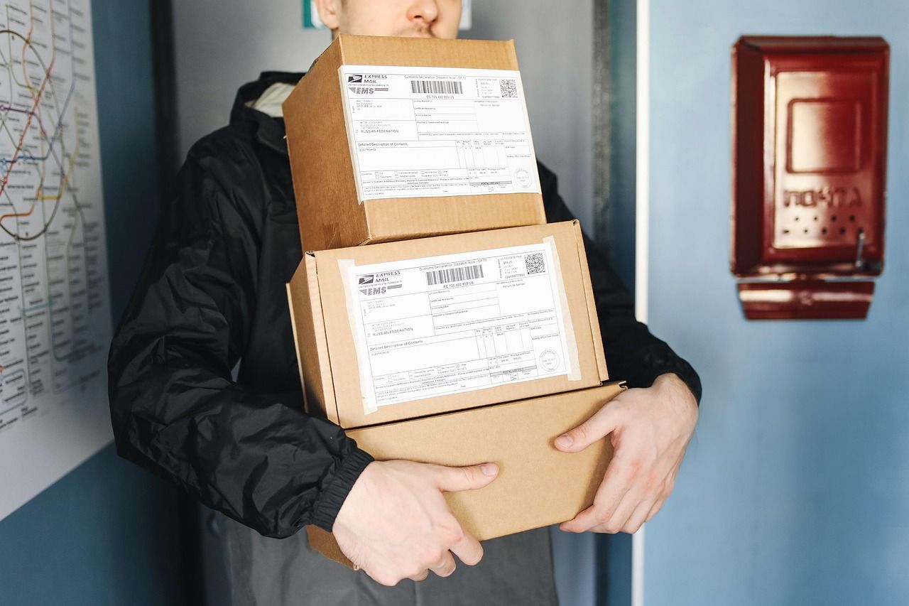 Livreur en uniforme tenant des colis et des boîtes de carton lors d'une tournée de distribution