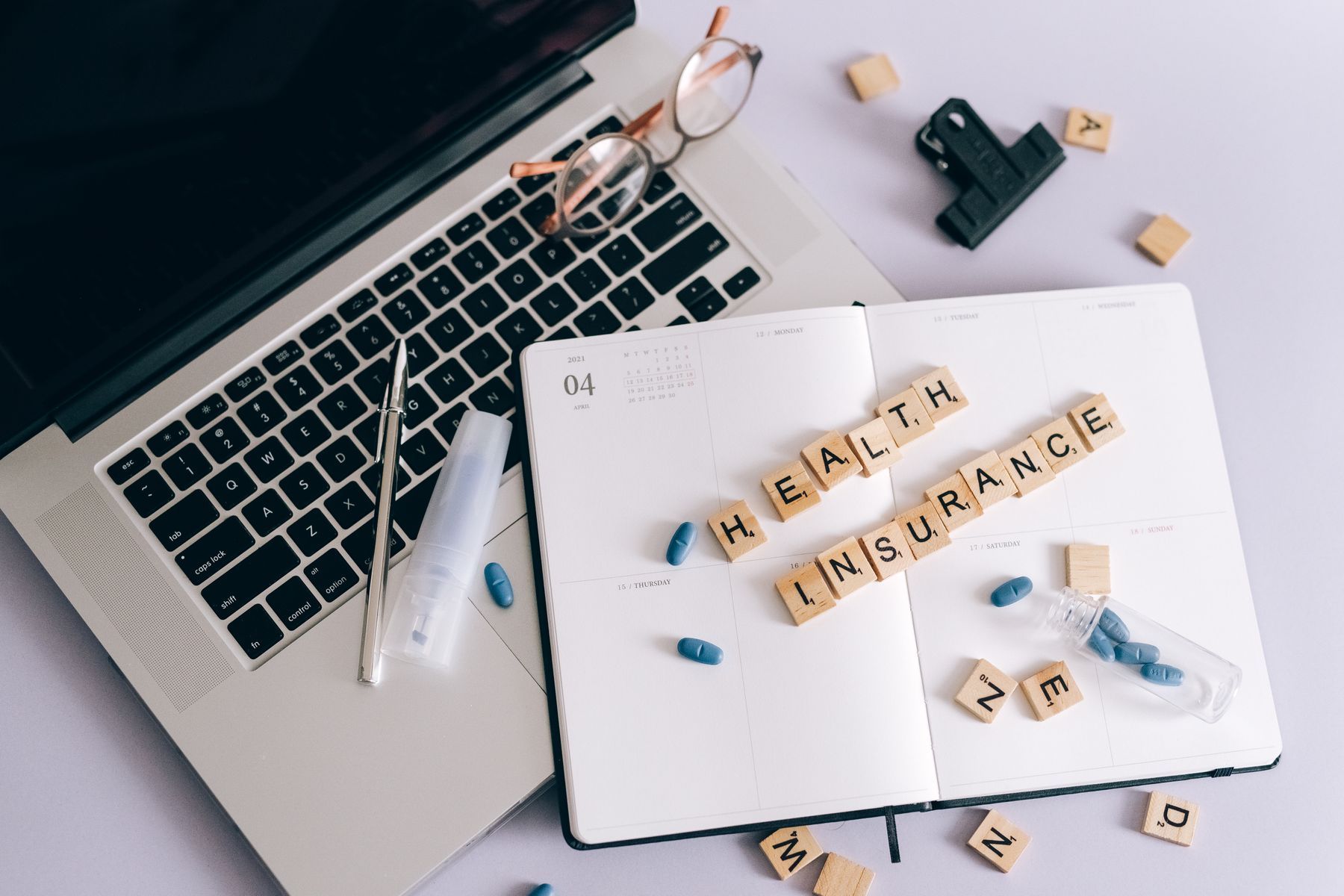 Ordinateur portable, carnet et pilules sur un bureau pour la gestion de l'assurance santé