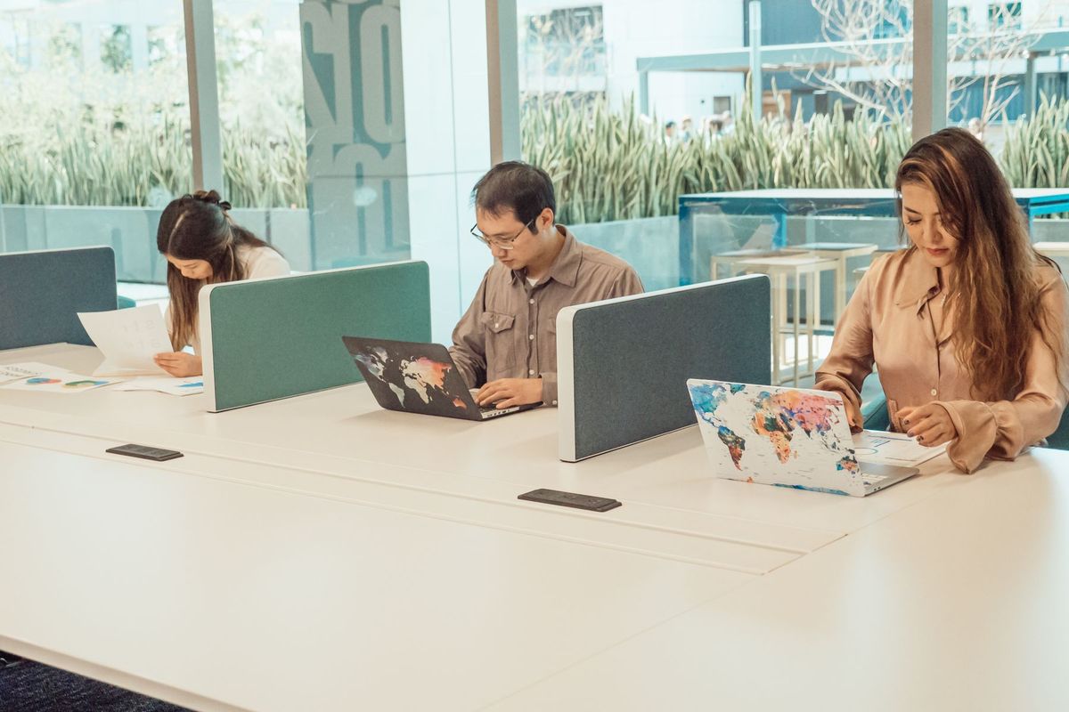 Équipe multidisciplinaire collaborant autour de postes de travail avec ordinateurs portables dans un espace de coworking moderne