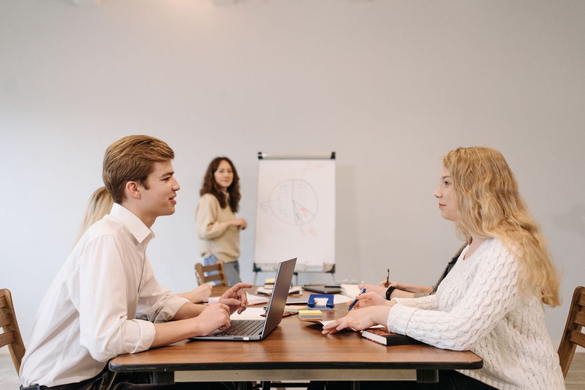 Équipe de professionnels collaborant autour d'un ordinateur portable et d'un tableau de travail