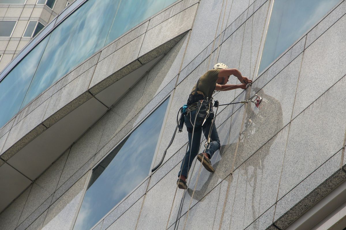 Ouvrier en chemise grise travaillant sur une façade de bâtiment