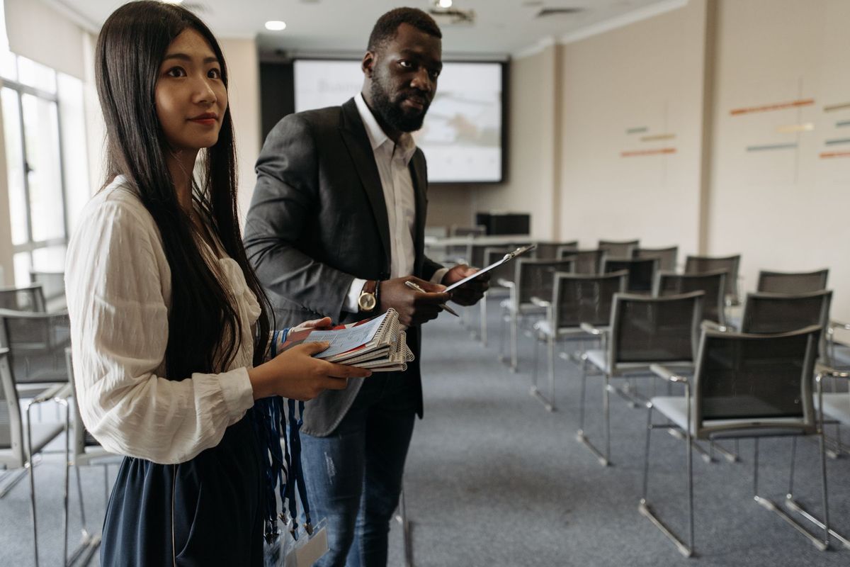 Deux formateurs consultent leurs notes lors d'une réunion pédagogique en salle de conférence
