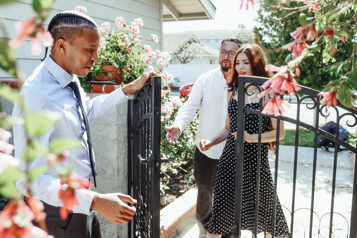 Agent immobilier présentant une maison à un couple devant l'entrée et le jardin