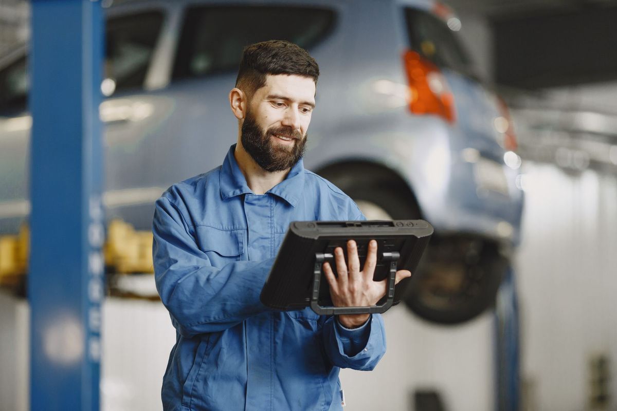 Mécanicien consultant une tablette dans son atelier de réparation automobile