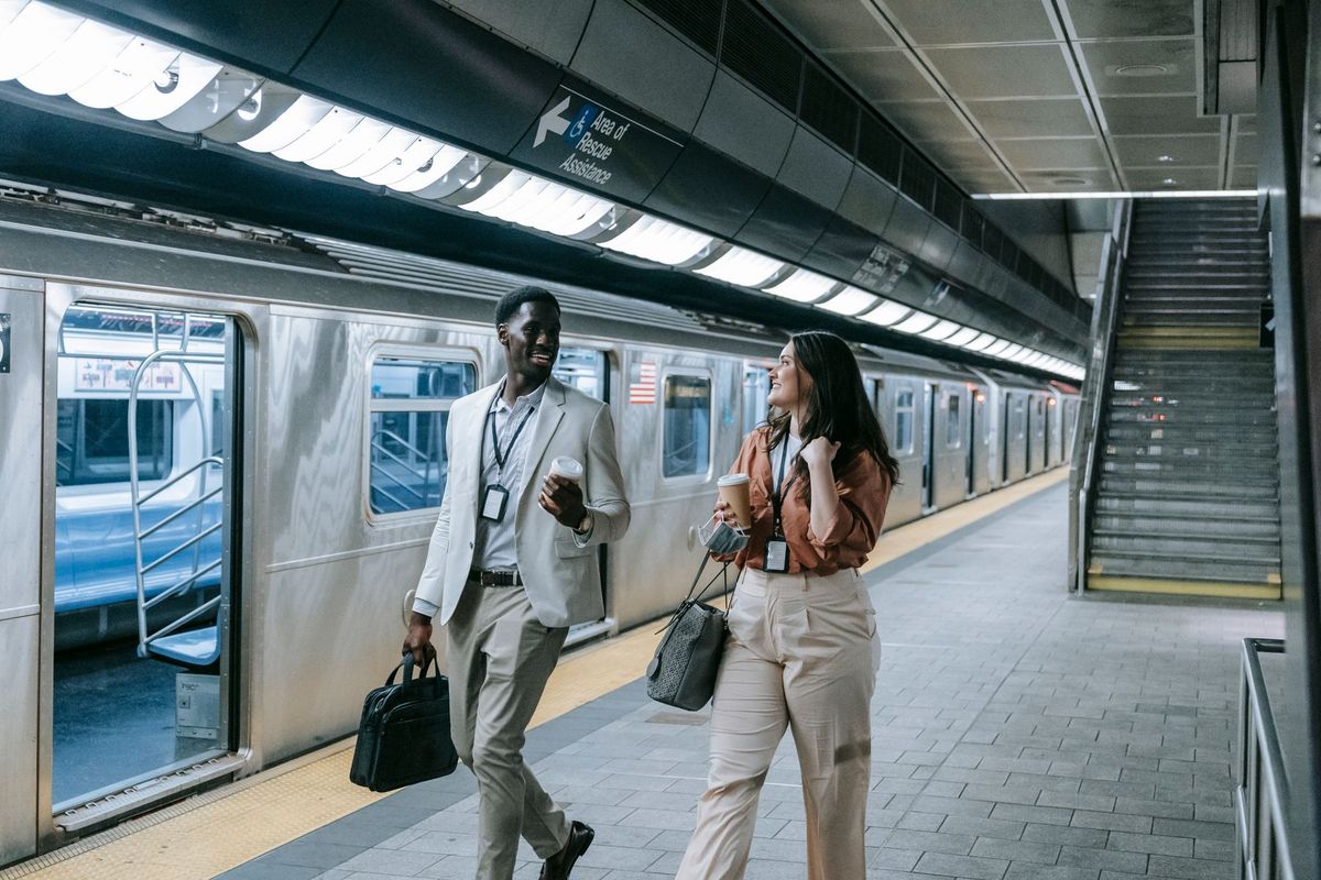 Deux professionnels discutent sur un quai de métro avec café et bagages