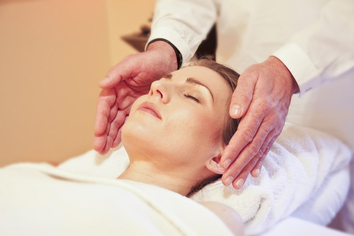 Praticienne reiki plaçant ses mains au-dessus du dos d'une cliente allongée pour un soin énergétique