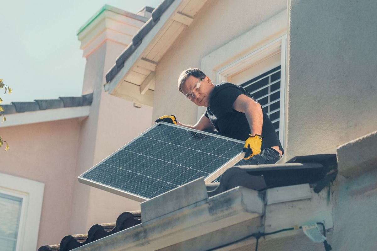 Technicien en équipement de sécurité installant des panneaux solaires sur un toit résidentiel