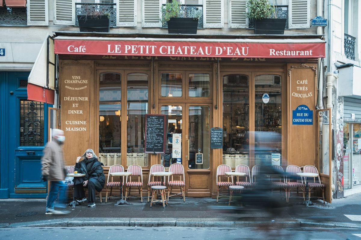 Deux personnes attablées en terrasse d'un restaurant discutent autour d'un repas