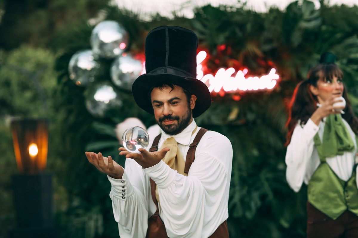 Magicien manipulant une boule de cristal lors d'une performance en plein air devant un public fasciné