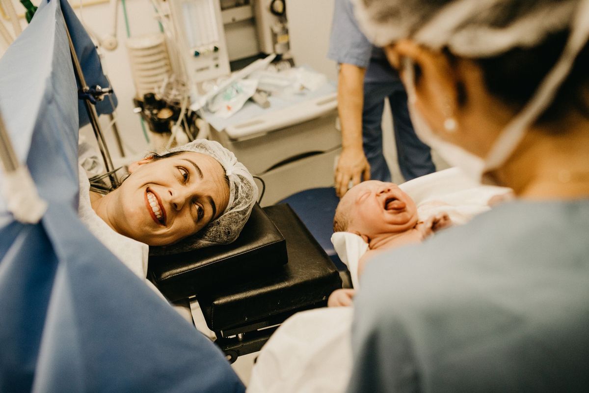 Une sage-femme accompagne une mère et son nouveau-né dans une salle d'accouchement