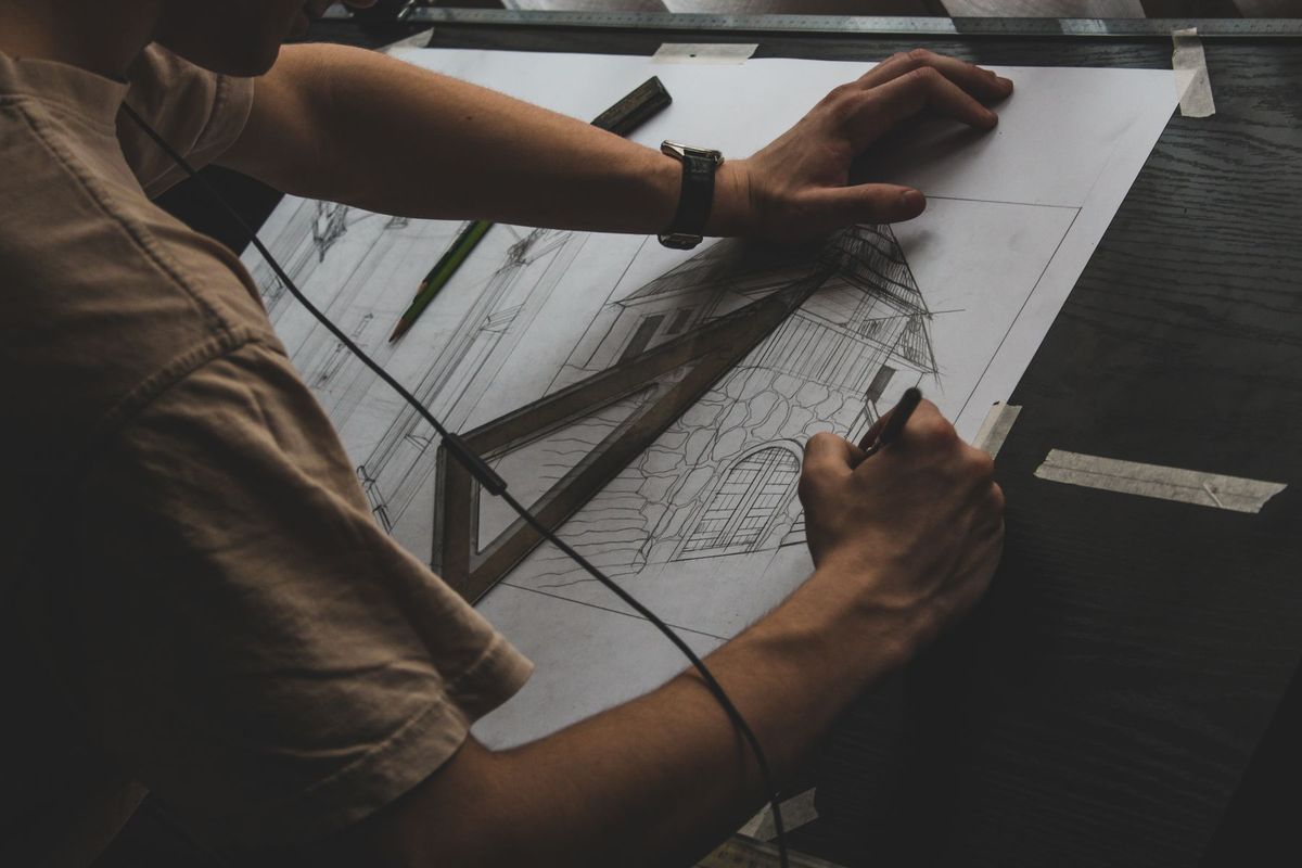 Architecte dessinant des plans techniques avec équerre et crayon sur sa table à dessin