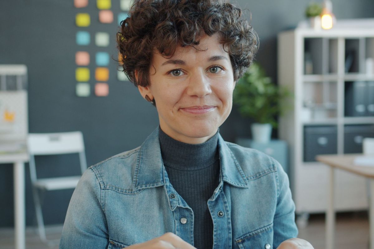 Jeune professionnel souriant dans un bureau moderne, travaillant sur son ordinateur portable