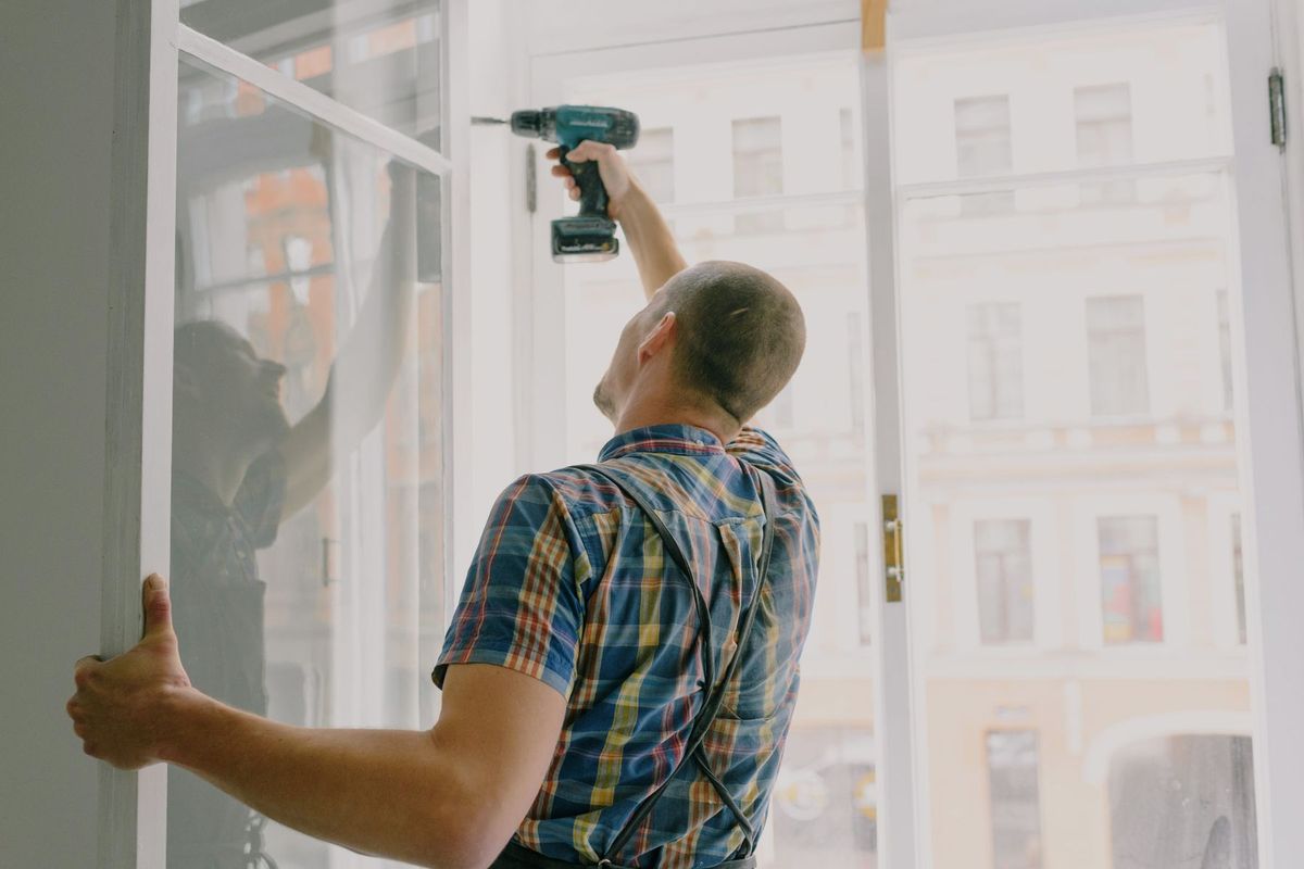 Artisan posant une fenêtre avec une perceuse lors d'une rénovation intérieure