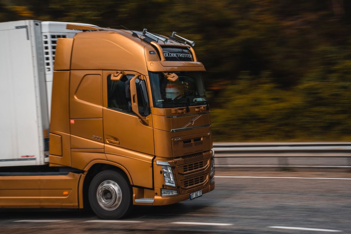 Camion orange circulant rapidement sur autoroute, symbolisant le secteur du transport et de la logistique