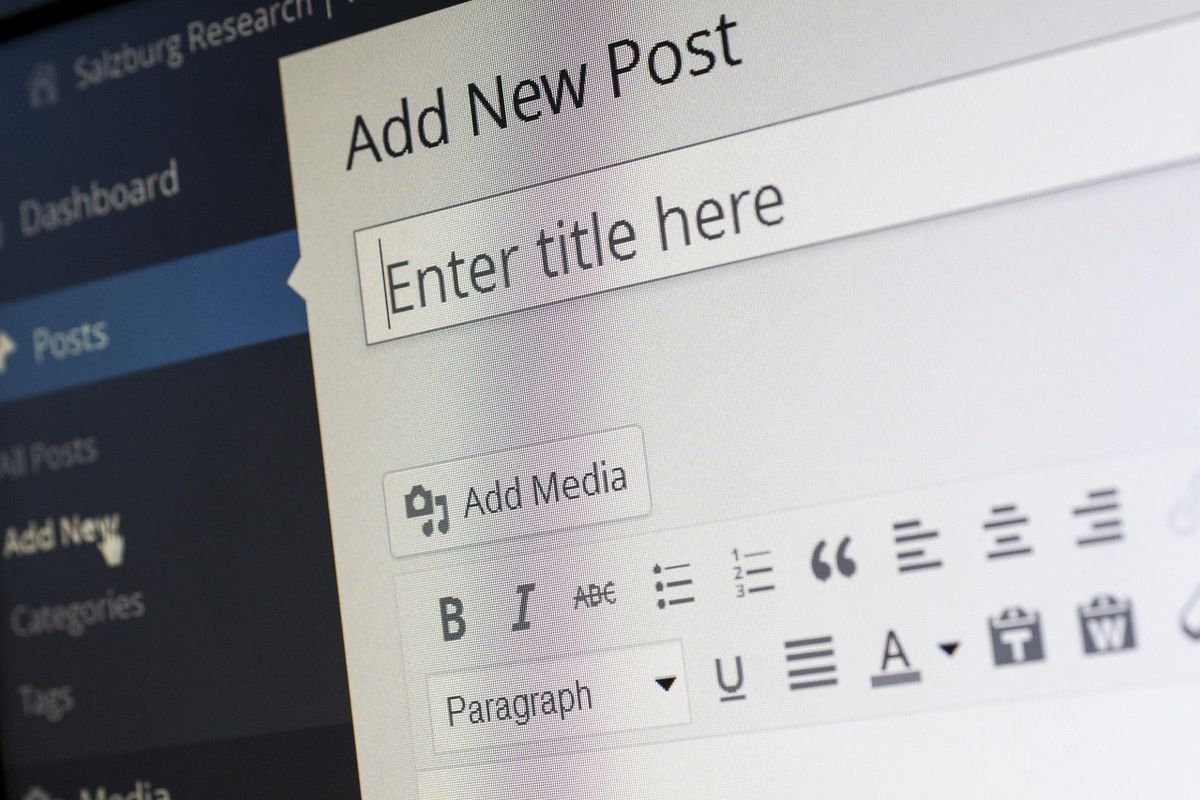 Personne tapant sur un clavier d'ordinateur pour rédiger et publier du contenu en ligne