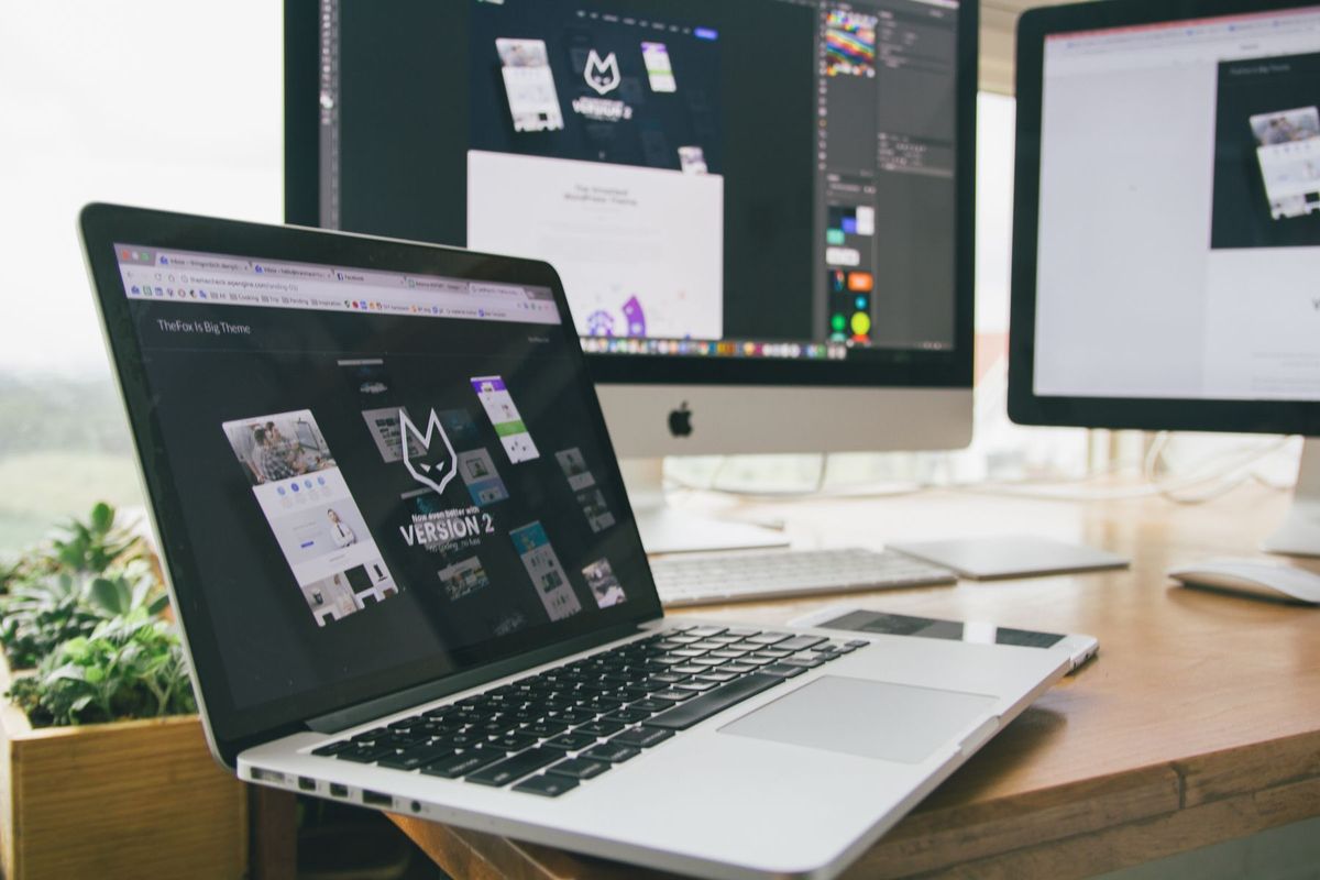 Designer travaillant sur plusieurs écrans avec des outils de création graphique