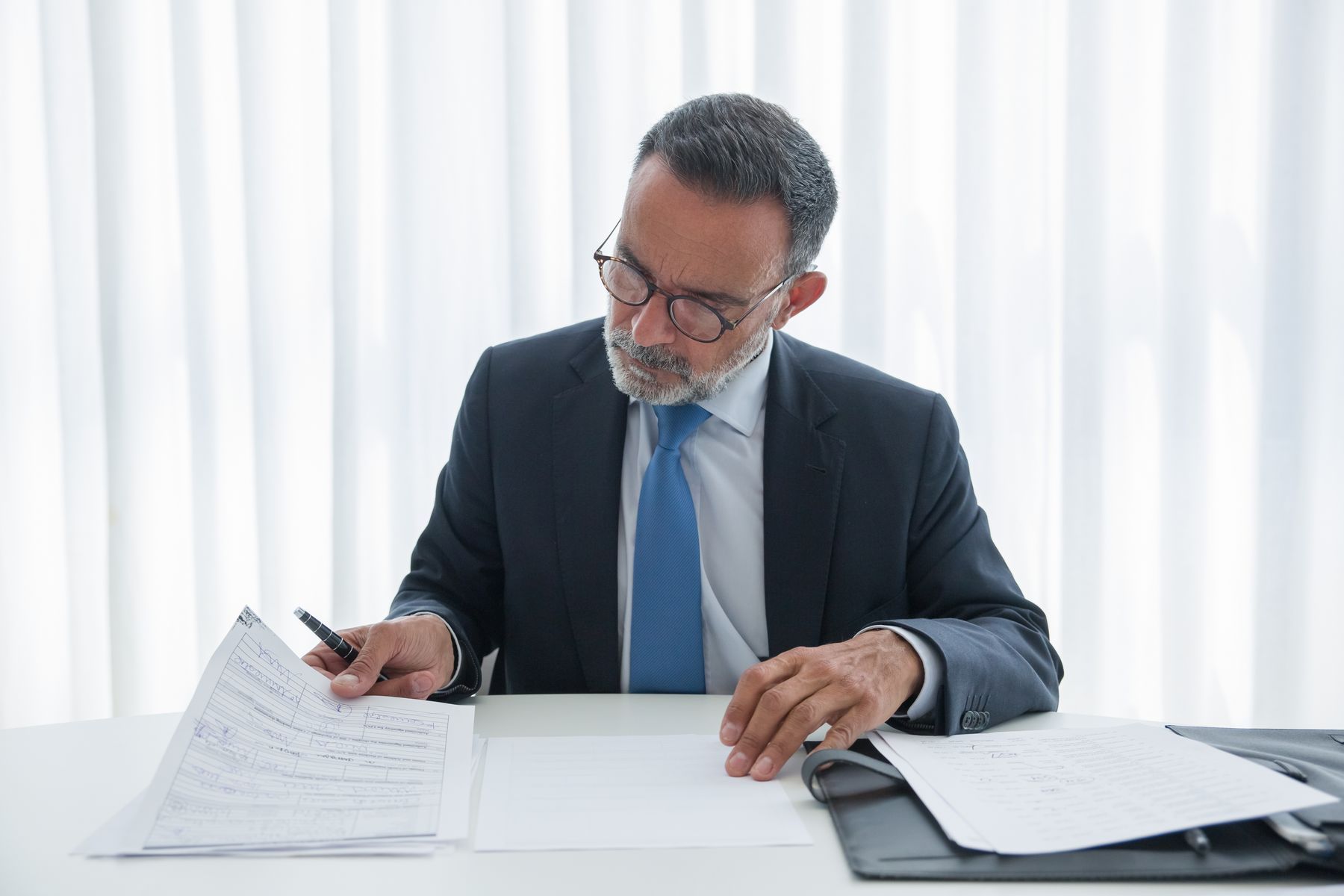 Dirigeant en costume consulte des documents importants à son bureau