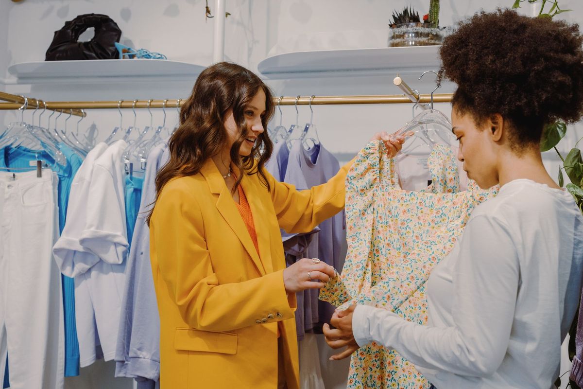 Deux vendeuses conseillent une cliente sur des vêtements dans leur boutique de mode