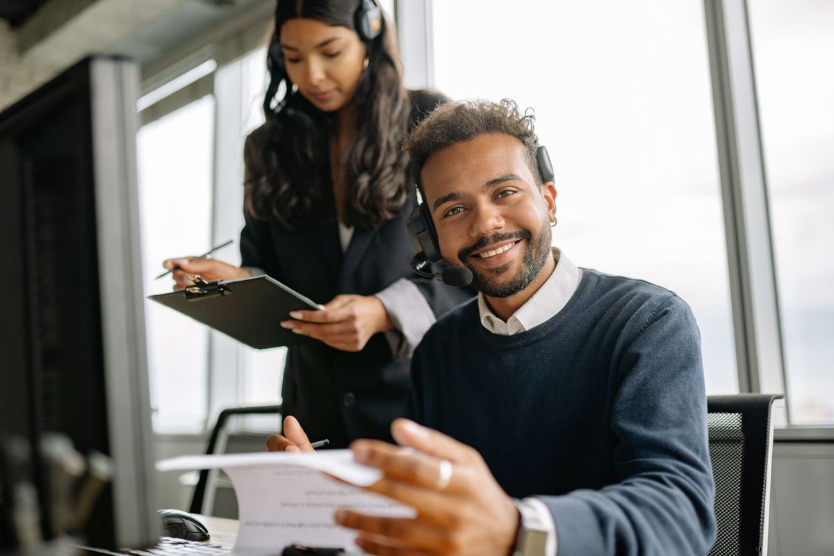 Consultant en communication engagé dans un appel professionnel au casque, souriant à son poste de travail