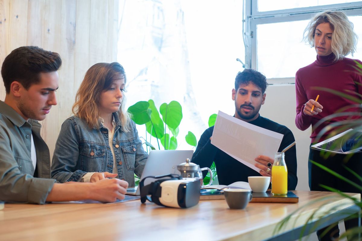 Quatre jeunes collaborateurs discutent autour d'une table dans un bureau lumineux et contemporain