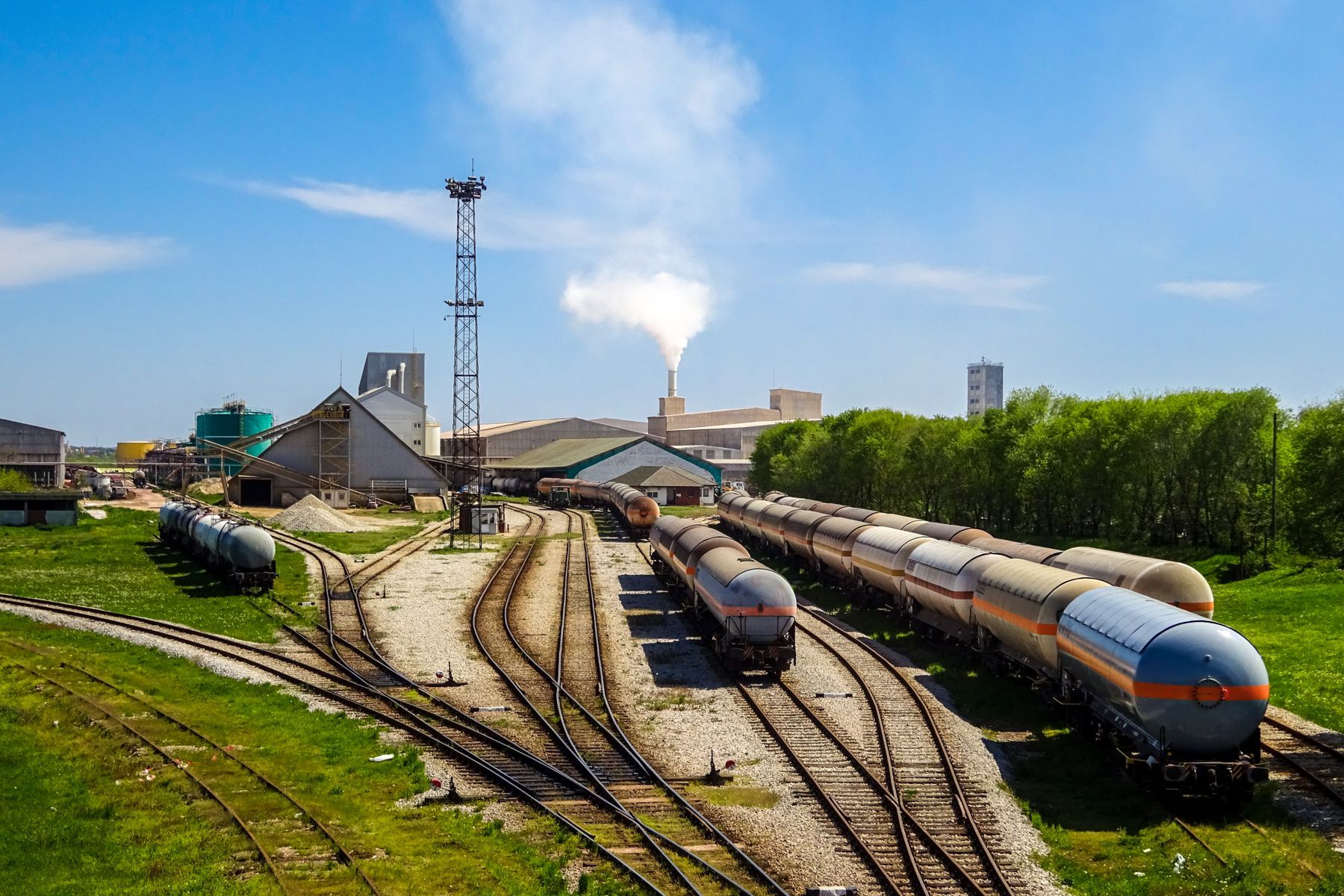 Wagons de marchandises alignés dans un parc ferroviaire industriel avec cheminées fumantes