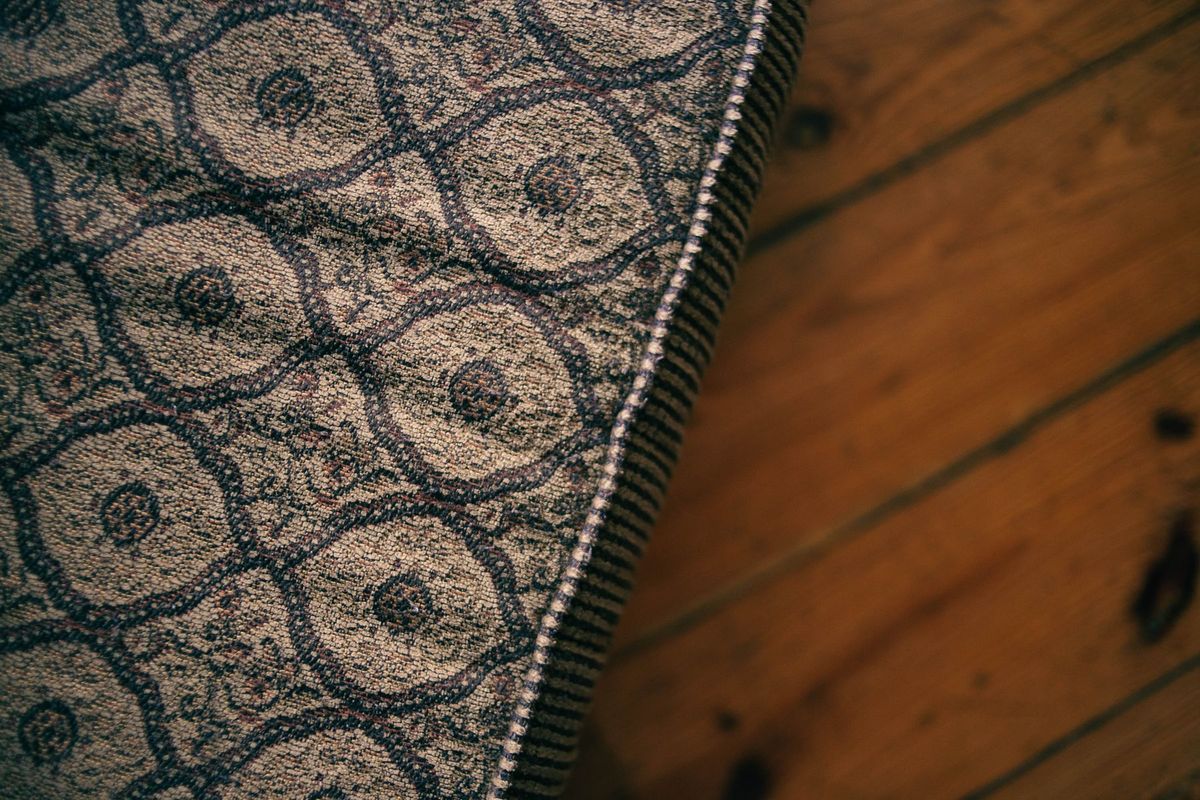 Détail d'un tissu à motifs sur un matelas montrant le travail de couture et de rembourrage du tapissier
