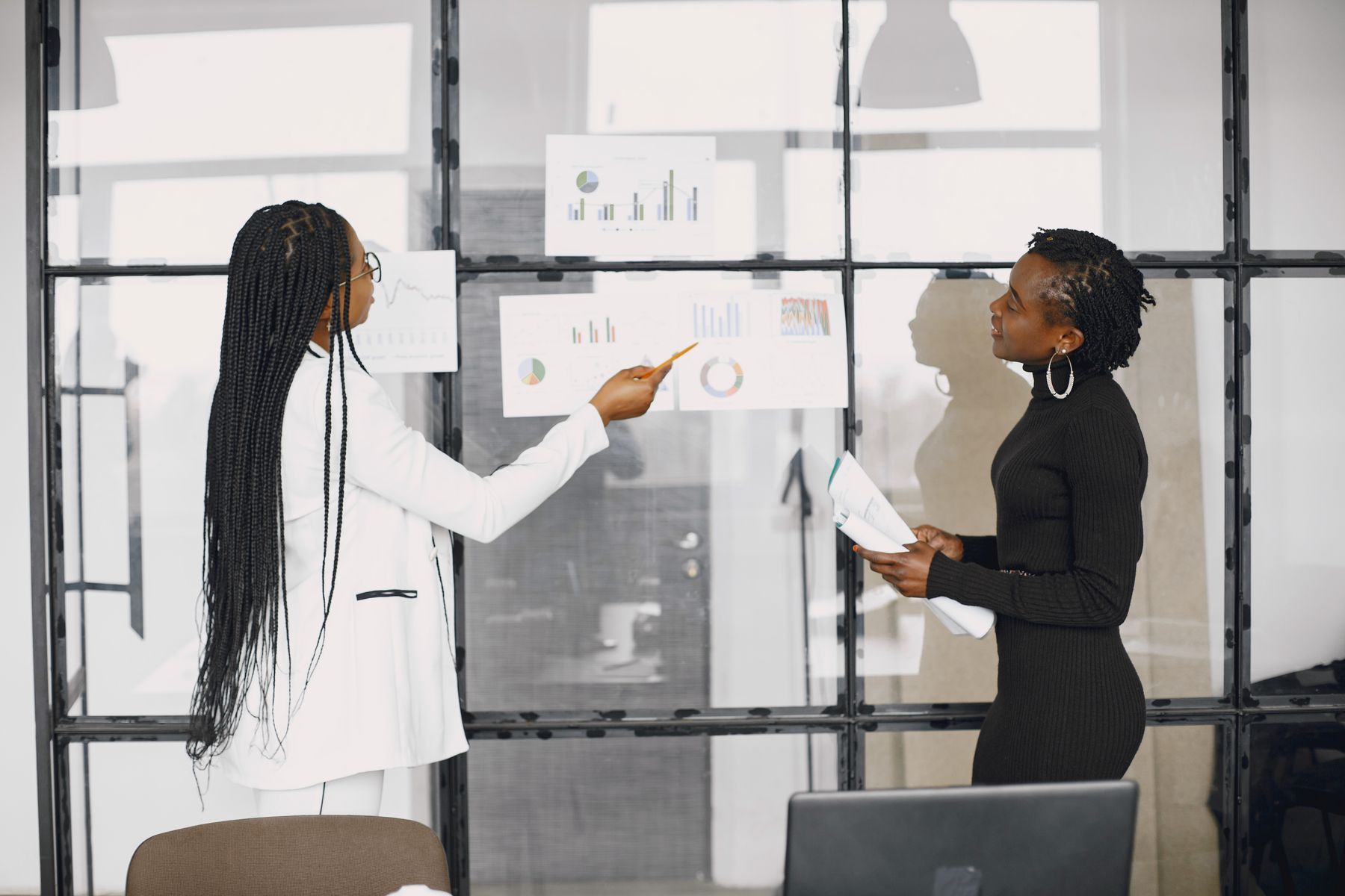 Deux femmes analysent des graphiques financiers sur un écran dans un bureau moderne