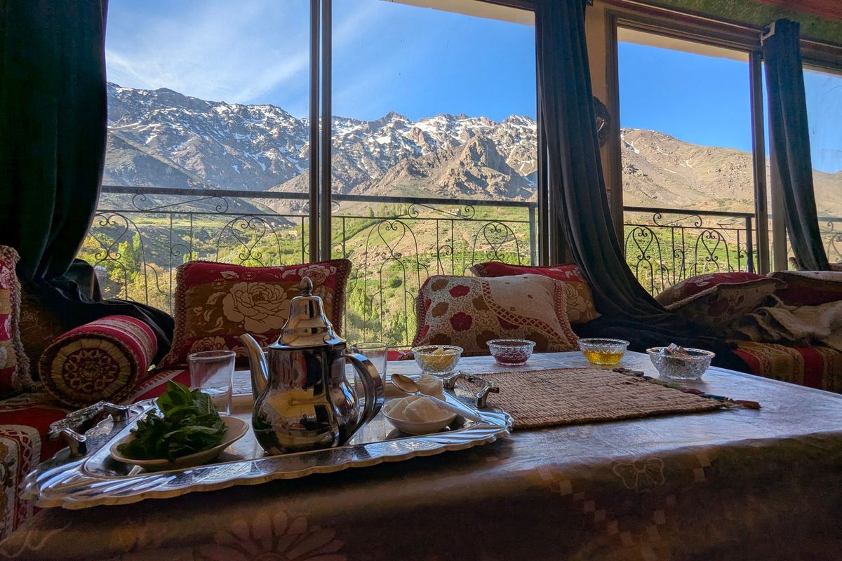 Théière et verres de thé traditionnel marocain posés sur une table avec vue sur les montagnes de l'Atlas