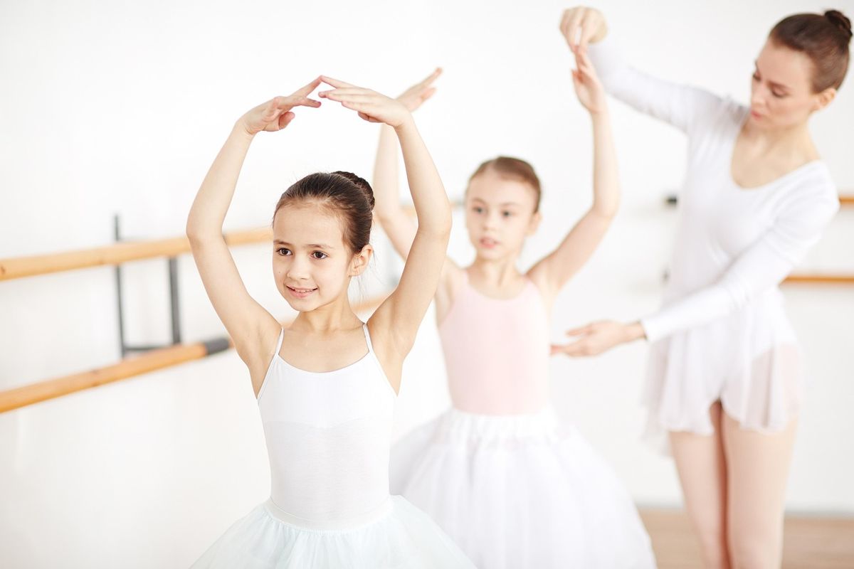 Enfants en tenue de ballet exécutant une arabesque en classe sous la supervision d'une instructrice