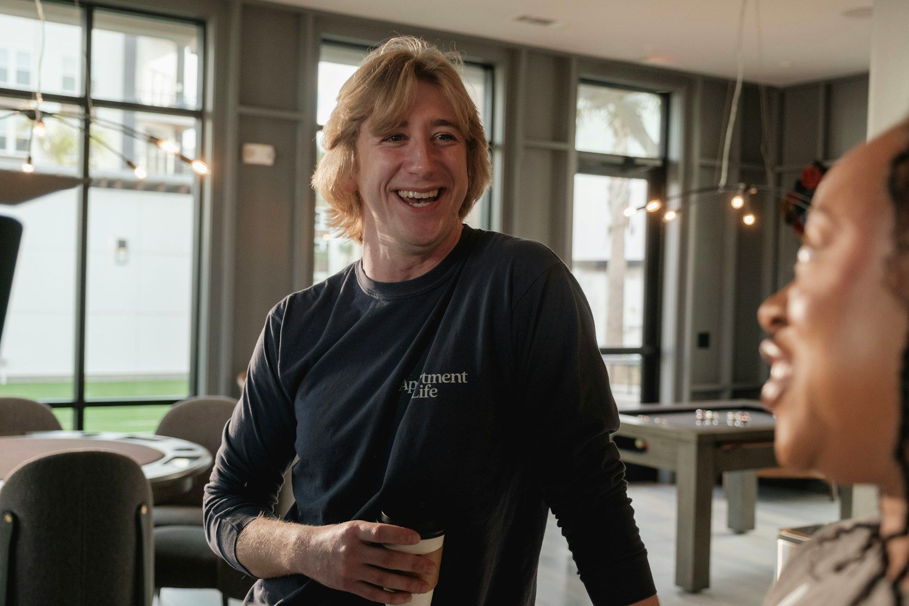 Homme aux cheveux blonds souriant en tenant un verre lors d'une réception professionnelle