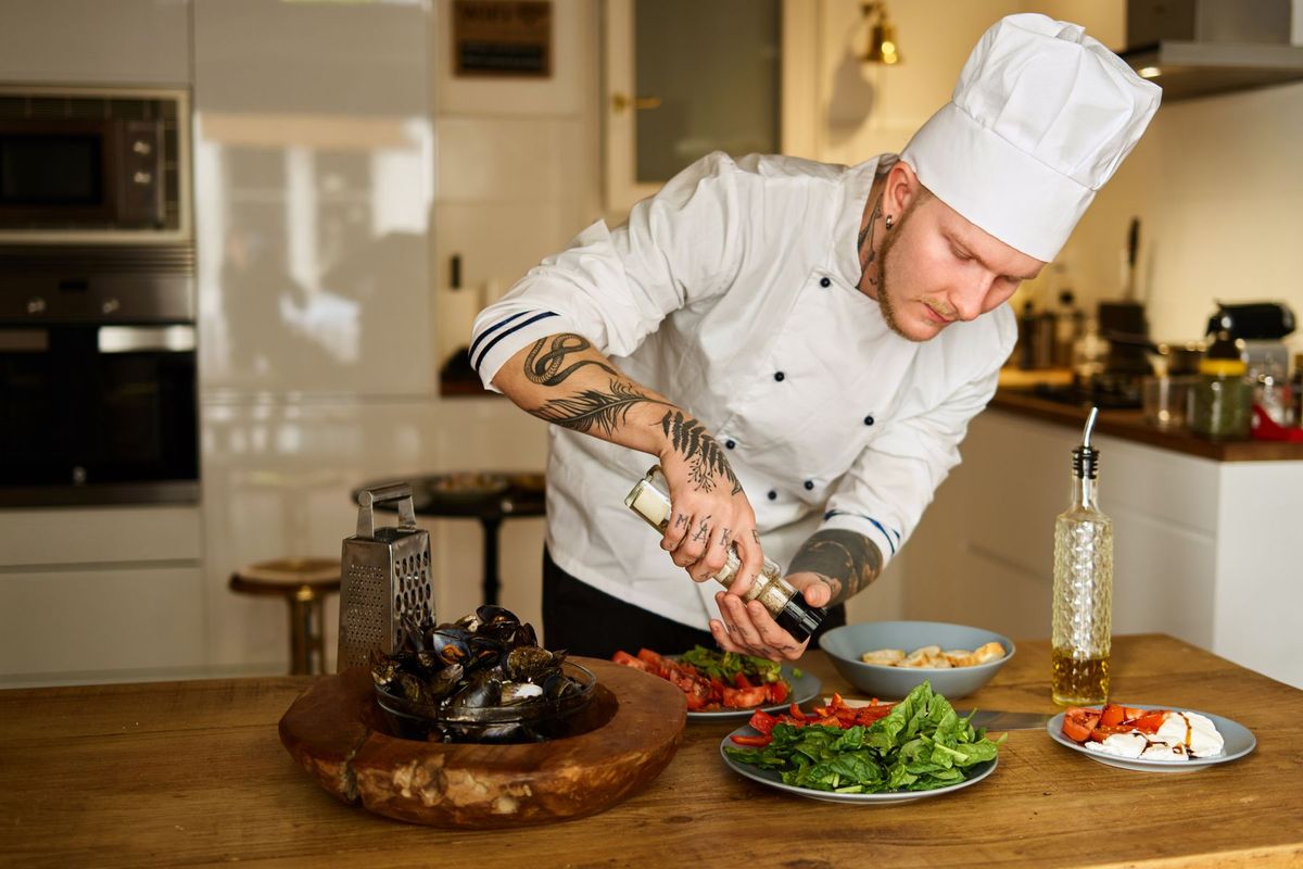 Chef versant une sauce sur des légumes frais dans une cuisine moderne