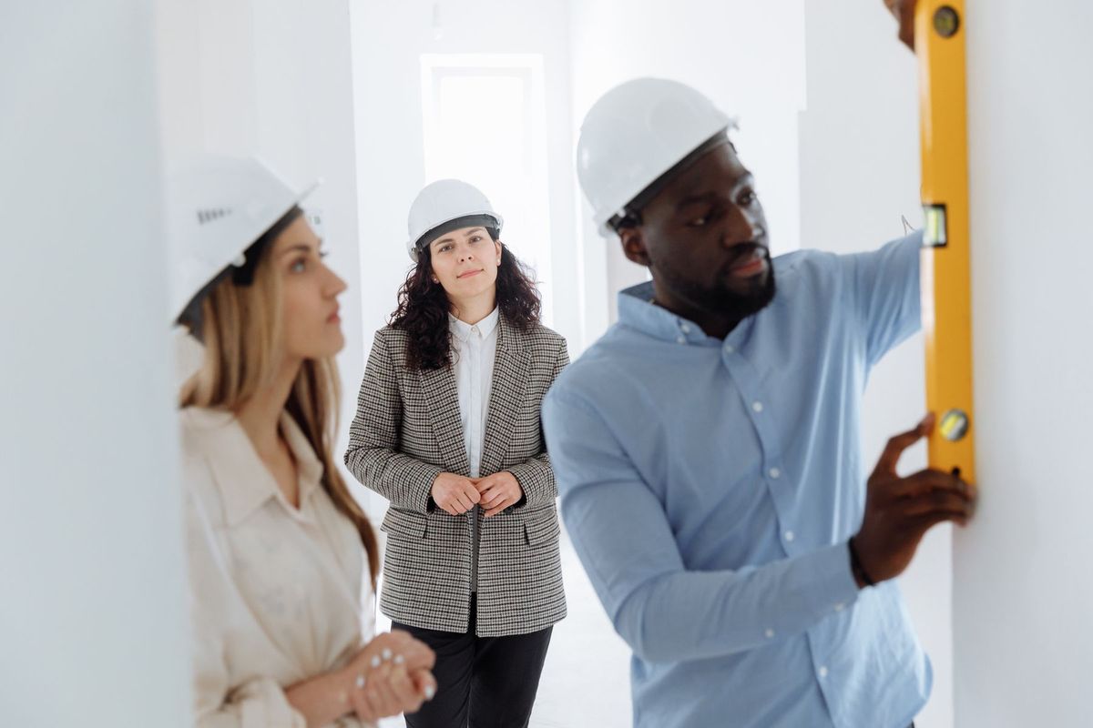 Équipe de professionnels vérifiant les mesures d'un chantier avec un niveau à bulle