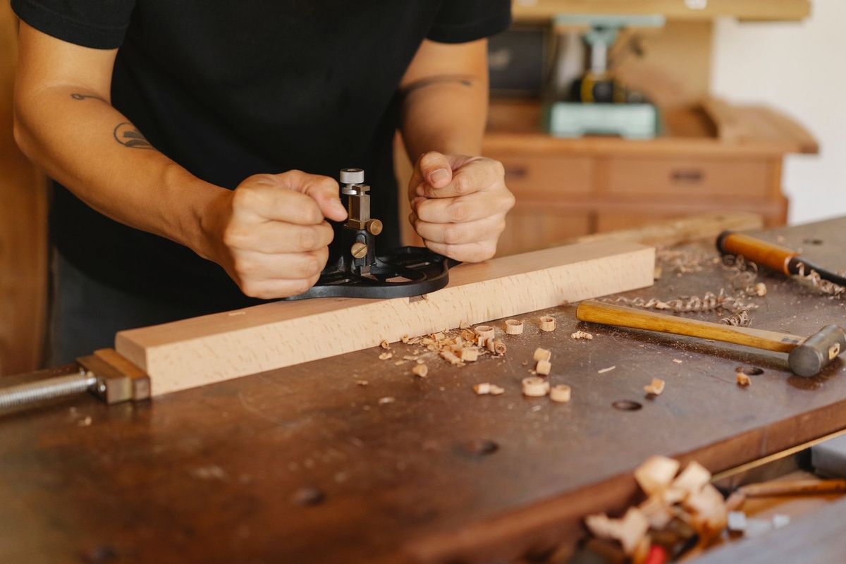 Artisan travaillant le bois avec précision à l'aide d'outils manuels dans son atelier