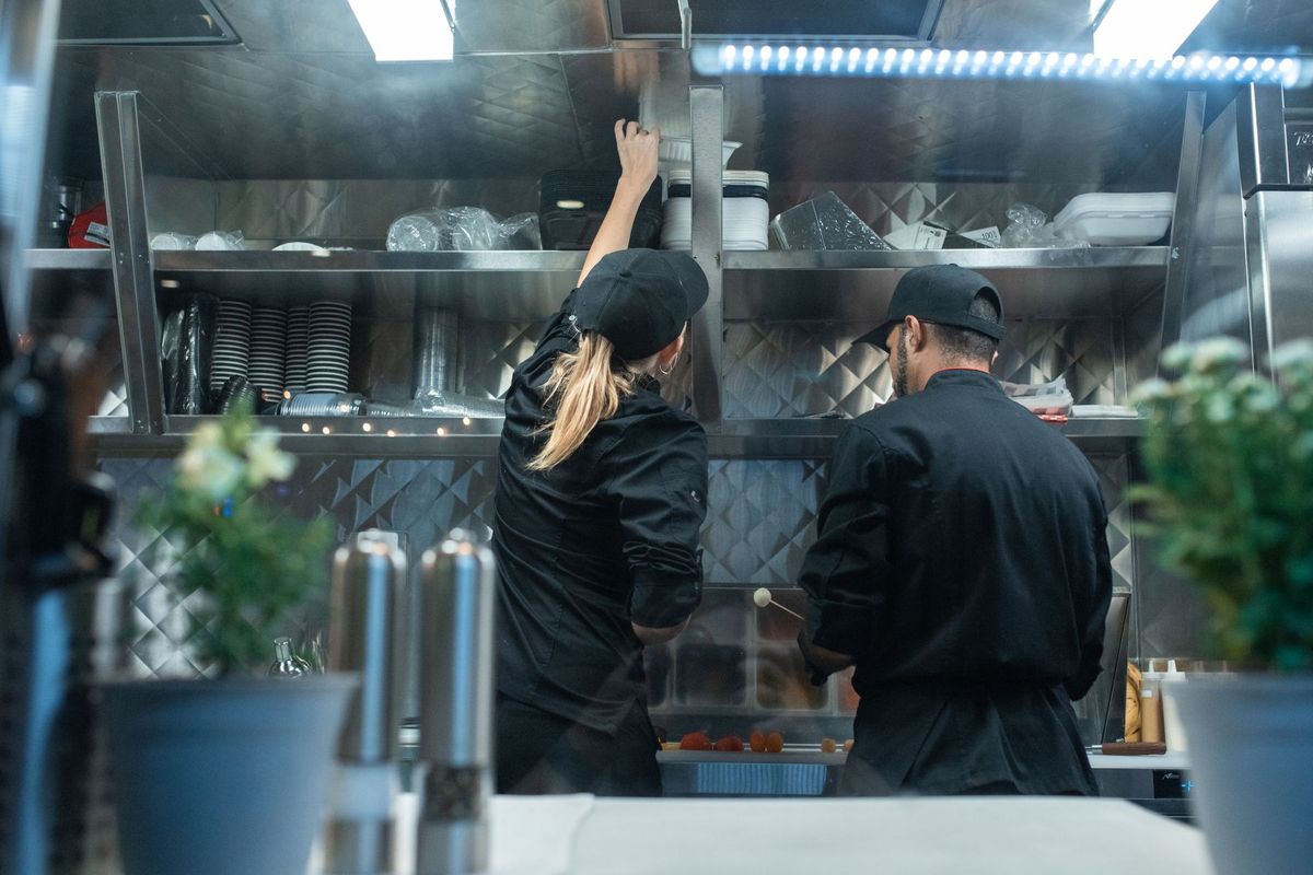 Deux cuisiniers en tenue professionnelle préparent des plats dans une cuisine moderne