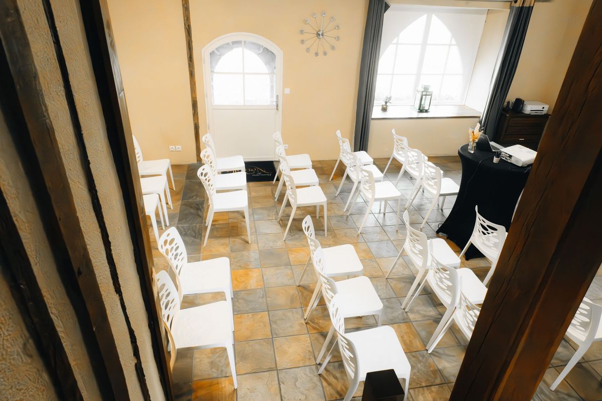 Responsable d'événement animant une réunion dans une salle claire avec chaises blanches et lumière naturelle