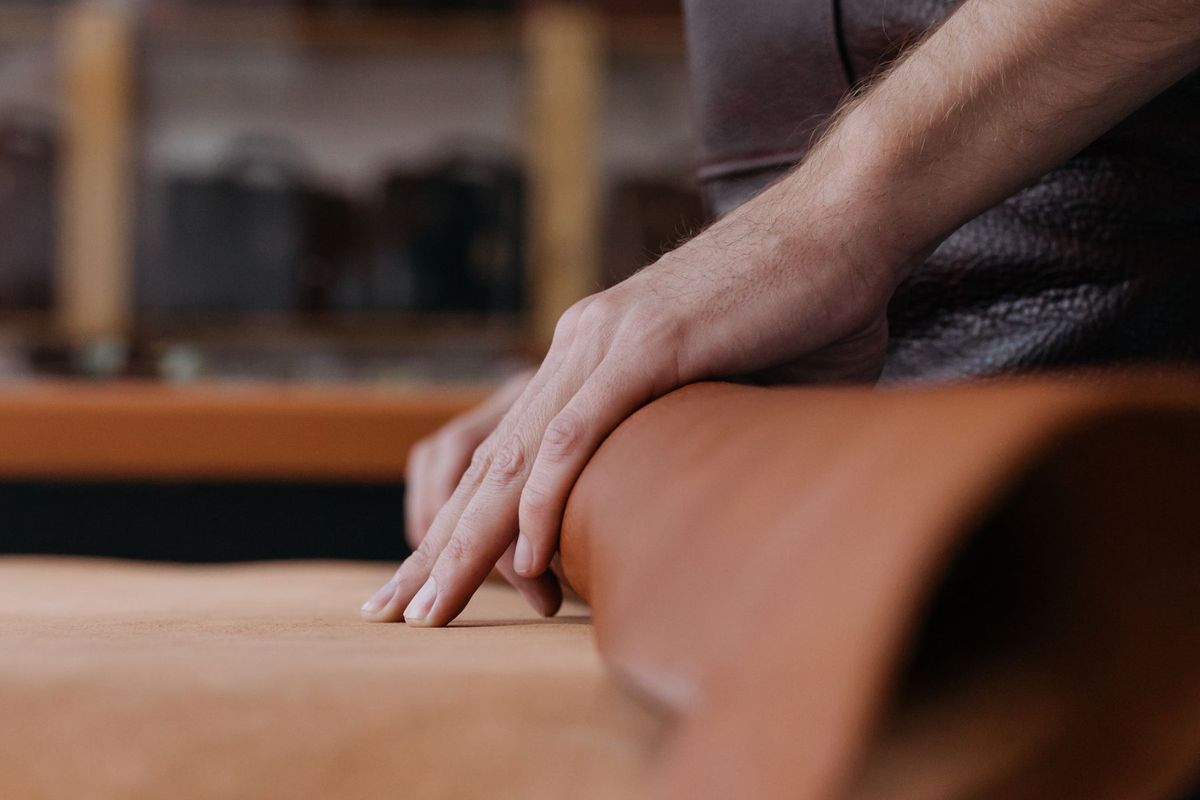 Mains expertes façonnant et cousant le cuir sur un établi d'atelier